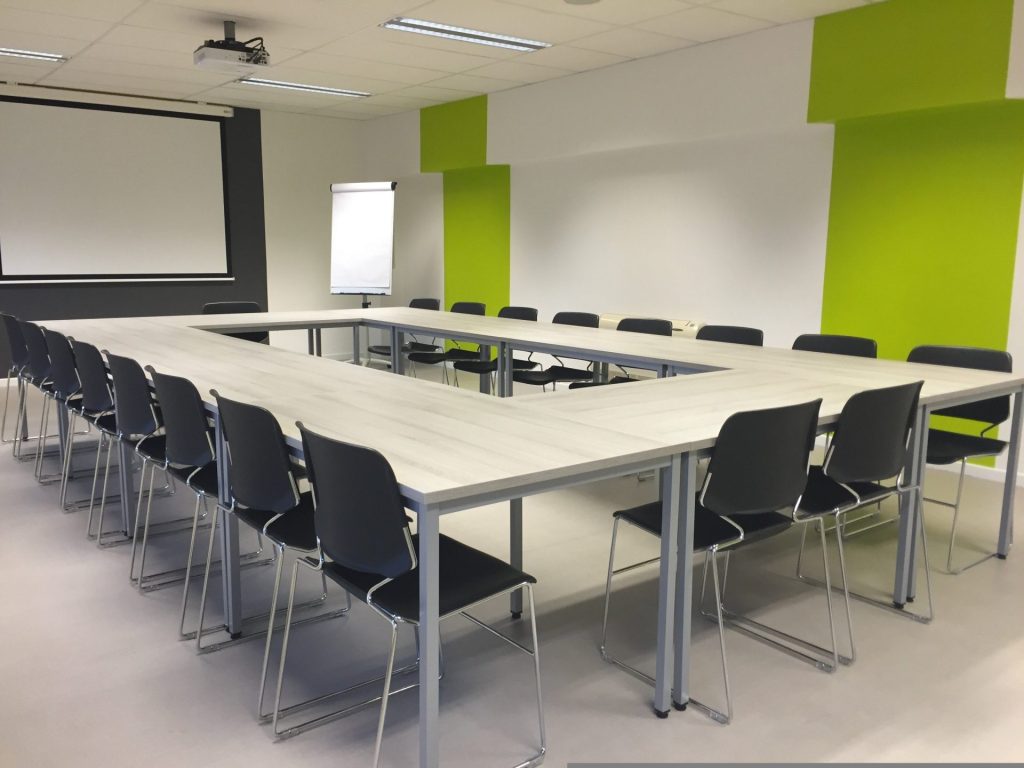 Salle de réunion avec une table rectangulaire et des chaises autour