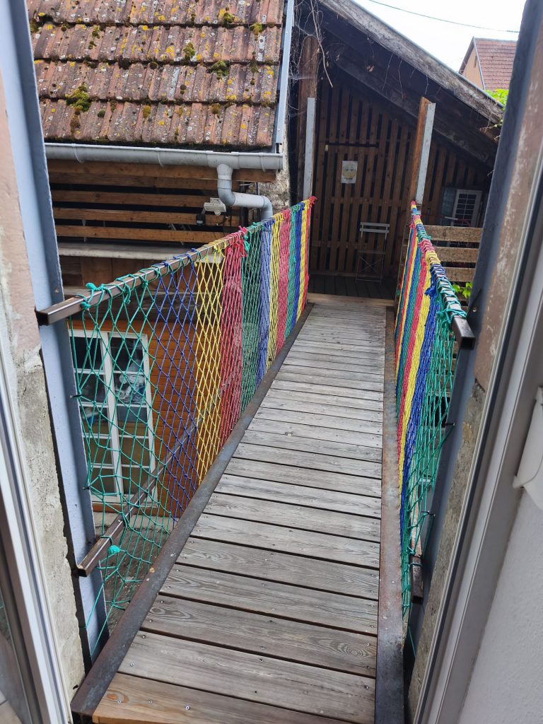 Petit pont de bois entre deux maisons.