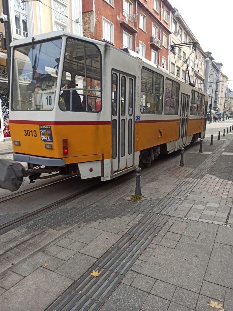 Vieux tram de couleur blanche et jaune. Ville en arrière plan.